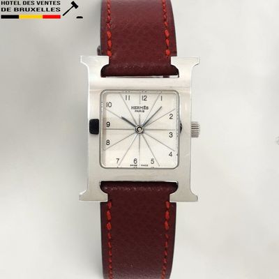 a close up of a watch on a white surface with a red strap