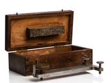 a small wooden box with a metal handle on a white surface
