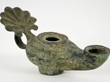 a small green vase that has a leaf on it