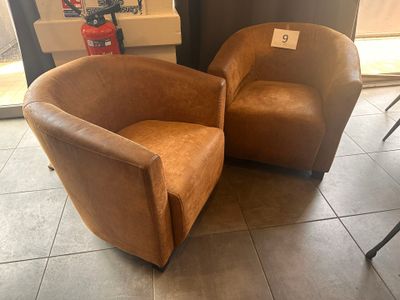 une paire de fauteuils en cuir marron placés dans une pièce près d'une fenêtre