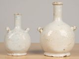 two white vases sitting on a table next to each other