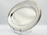 a silver plate on a stand on a white surface