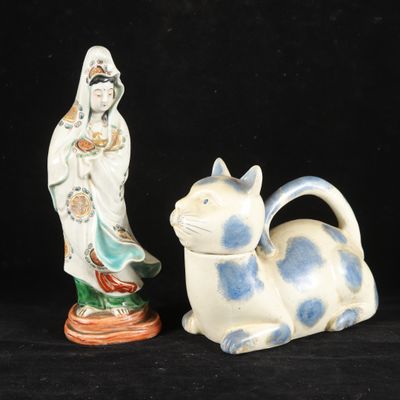 two ceramic figurines of a woman and a cat on a black background