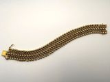 gros plan d'un bracelet en or sur une surface blanche