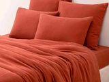 une photo d'un lit avec des draps et des oreillers orange