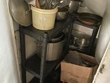 Des casseroles et des poêles sont empilées sur une étagère dans un coin de la cuisine.