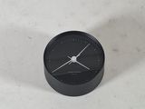 une petite horloge noire posée sur une table blanche
