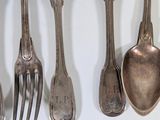 a lot of spoons and forks hanging on the wall