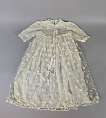 une robe blanche ornée de fleurs blanches et d'un ruban blanc autour du cou