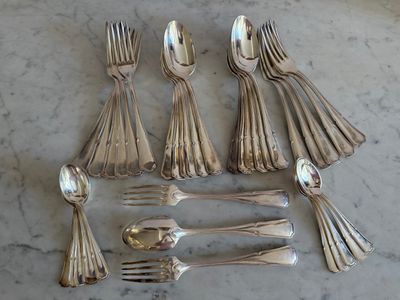 un grand nombre de cuillères et de fourchettes en argent disposées sur une table