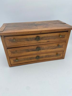 a small wooden chest with three drawers on top of it