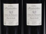 three bottles of red wine are lined up on a shelf
