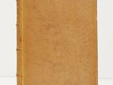 un vieux livre à la couverture brune posé sur une surface blanche