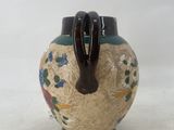 a small vase with a handle on it on a white surface