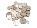 a pile of old silver coins on a white surface
