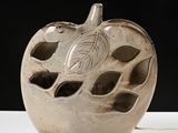 a white apple shaped vase with a leaf design on it