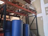 some blue barrels are stacked on top of a pallet in a warehouse