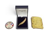 une petite broche en or et une pièce de monnaie dans une boîte