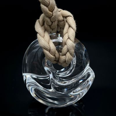 un vase en verre contenant une corde, posé sur une surface noire