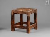 an old wooden stool sitting on top of a gray surface