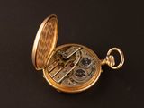 an image of a gold pocket watch on a black surface