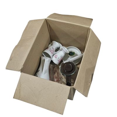 une boîte en carton remplie d'objets divers posée sur une surface blanche