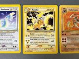 Trois cartes Pokémon sont posées les unes sur les autres sur une table.