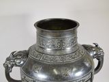a large silver vase with a handle on a table