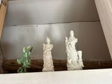 three statues sitting on top of a shelf next to a window