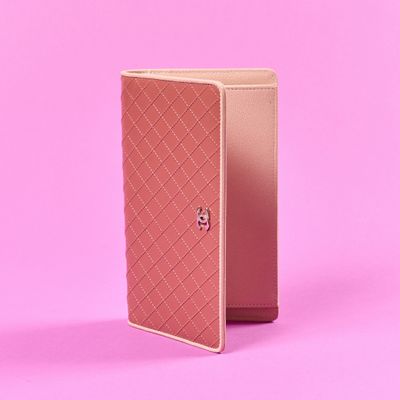 un étui à passeport rose posé sur une surface rose