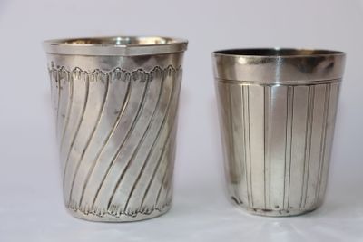 deux tasses en argent posées l'une à côté de l'autre sur une table