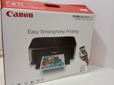 the box of a canon printer sitting on a table next to a cell phone