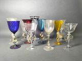 several different colored glass goblets are lined up on a gray surface