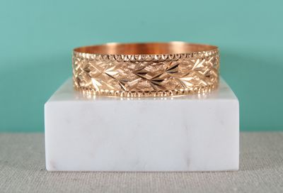 un gros plan d'une bague en or posée sur un bloc de marbre