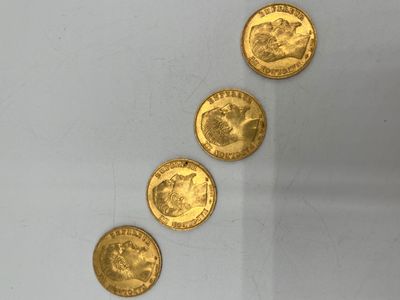 quatre pièces d'or sont disposées en ligne sur une surface blanche
