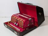 a red accordion sitting in a case on a white surface