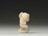 a carved ivory figurine of a monkey on a rock