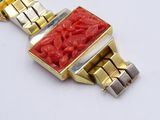 a gold and red bracelet with a red stone in the center