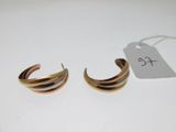 une paire de boucles d'oreilles créoles dorées avec une étiquette de prix sur fond blanc