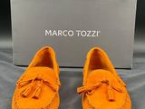 a pair of orange moccali shoes with a box in the background