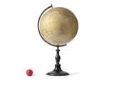 un petit globe et une boule rouge posés sur une surface blanche