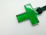 a green cross on a black cord on a white surface
