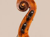 a close up of a violin neck with a fiddle in the background