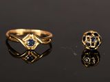 two gold rings with sapphires and diamonds on a black surface