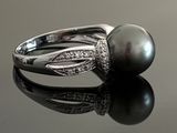 an image of a black pearl and diamond ring on a reflective surface