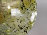 someone is holding a green and yellow stone in their hand