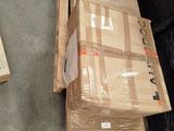 a large black bear sitting on the floor next to a pile of boxes