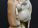 a small statue of a laughing buddha sitting on a pillow