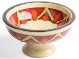 a red and yellow bowl sitting on top of a white pedestal