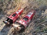 two cans of soda sitting on the ground next to a bush